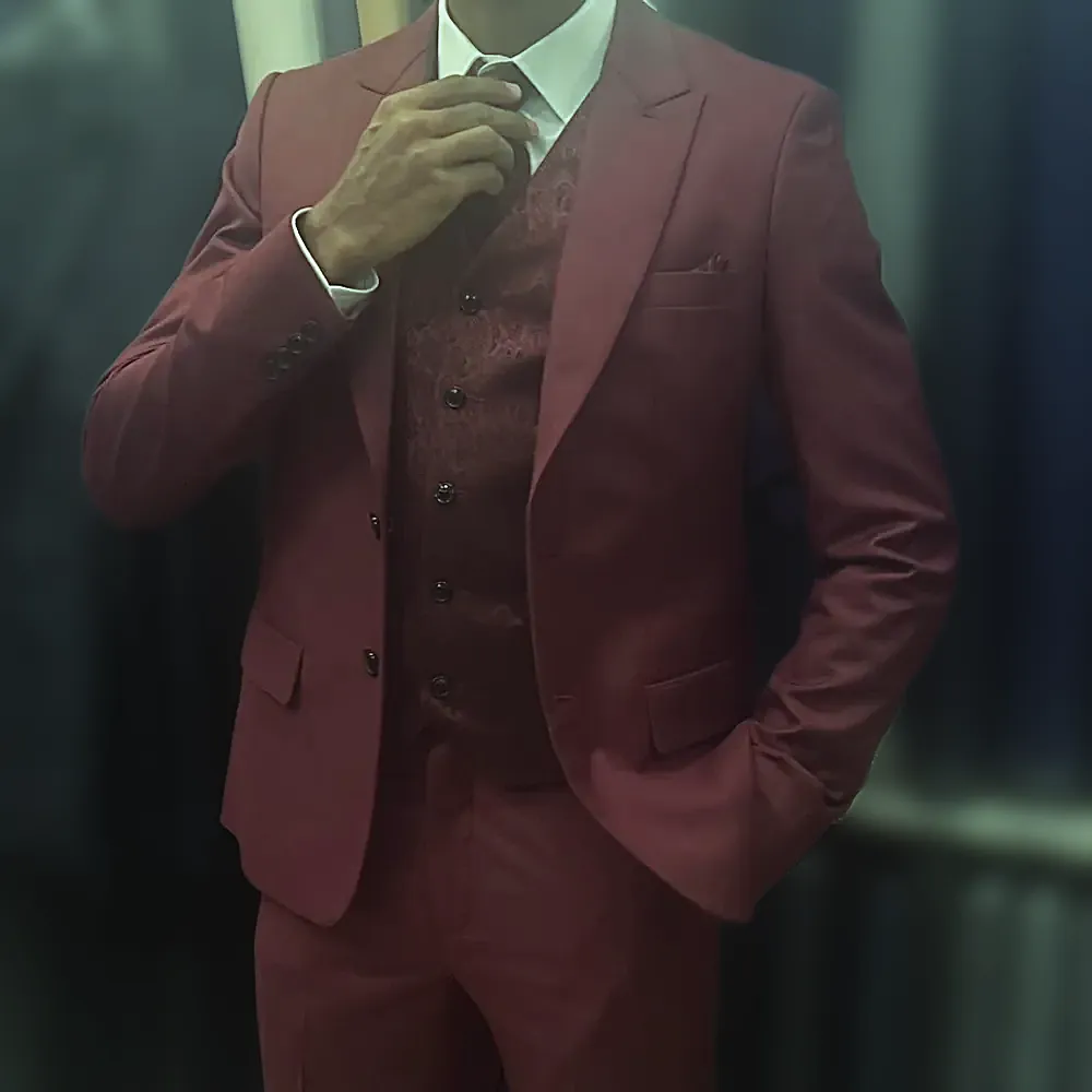 A burgundy three-piece suit with peak lapels and a patterned waistcoat