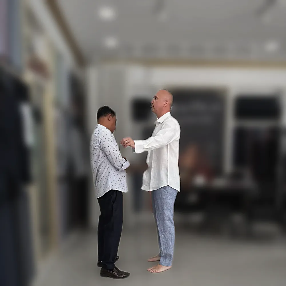 A fitting in progress: a white linen shirt and linen trousers, being adjusted at the cuff