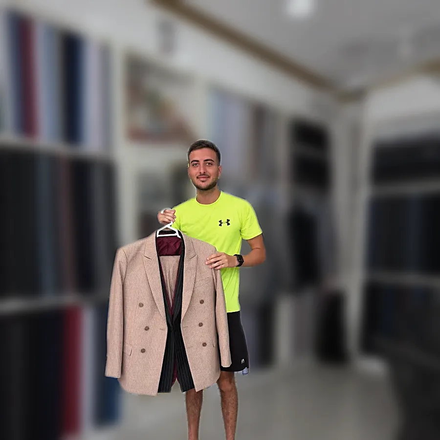 A client in the shop holding up a finished pale pink double-breasted coat — from Amir Jokar's review
