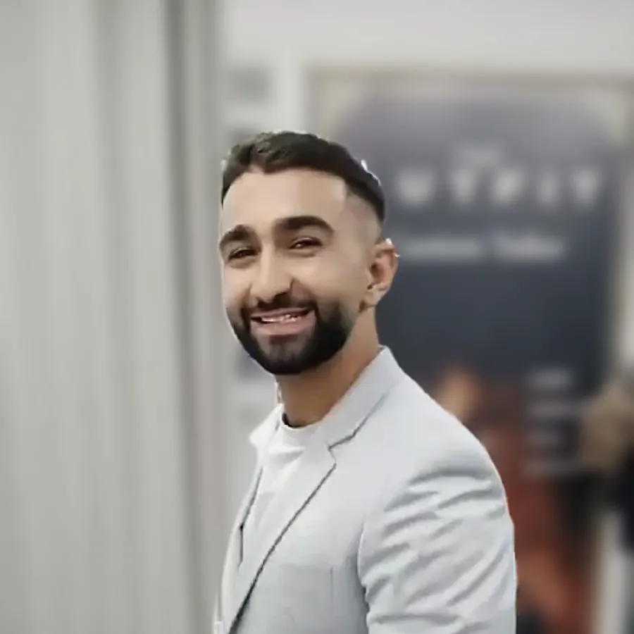 A client in a pale grey jacket, smiling, in front of the shop's sign — from Enes Ergor's review