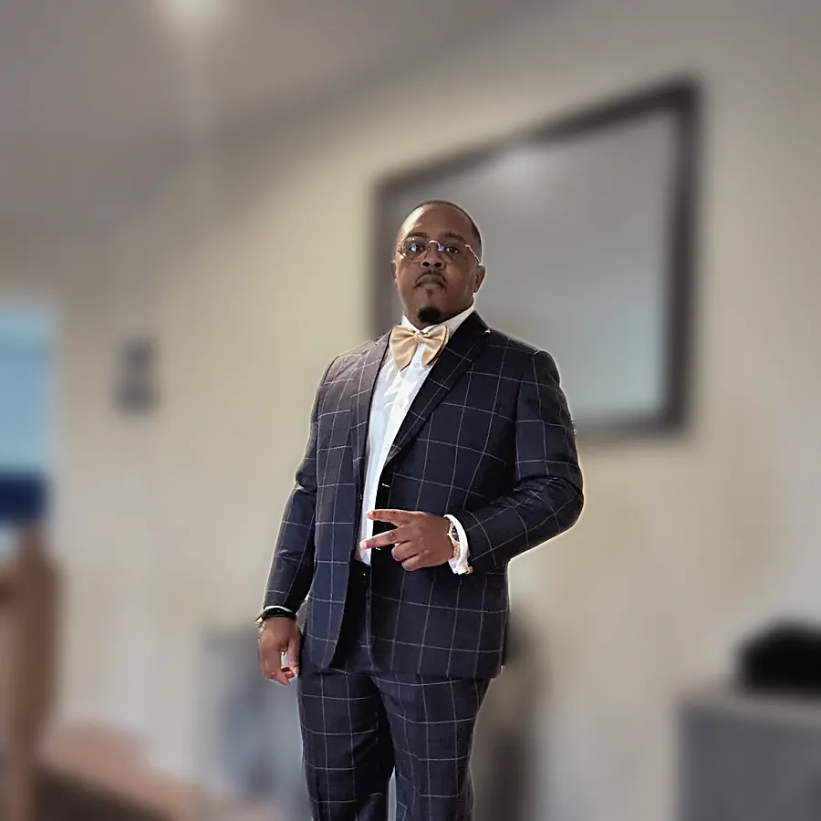 A client in a navy check suit and a gold bow tie standing in a hallway — from Harold White, Jr.'s review