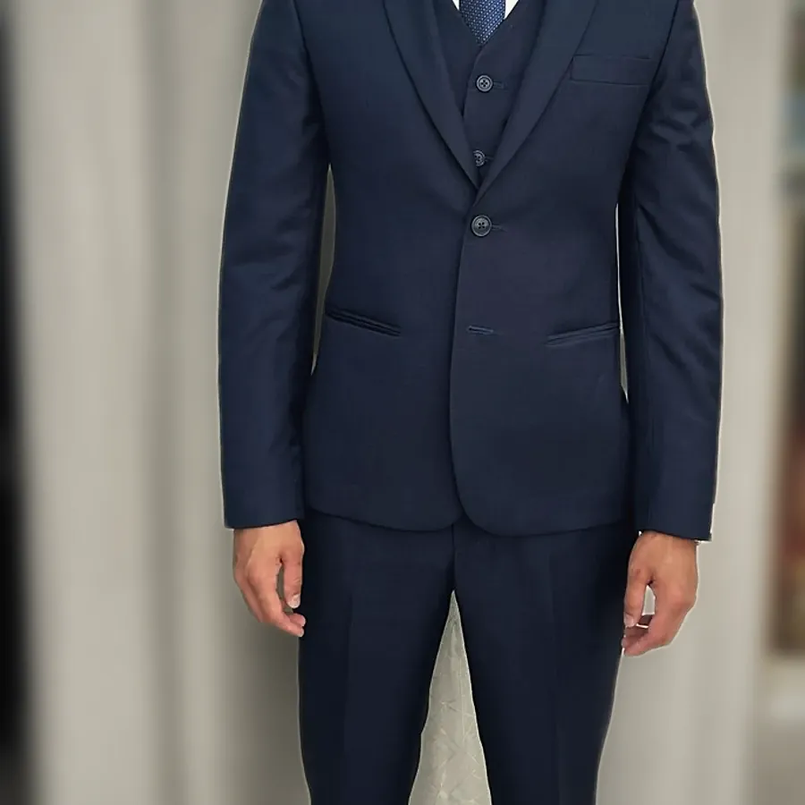 A navy three-piece suit with the jacket buttoned, seen from the chest down — from Medina Maxhera's review