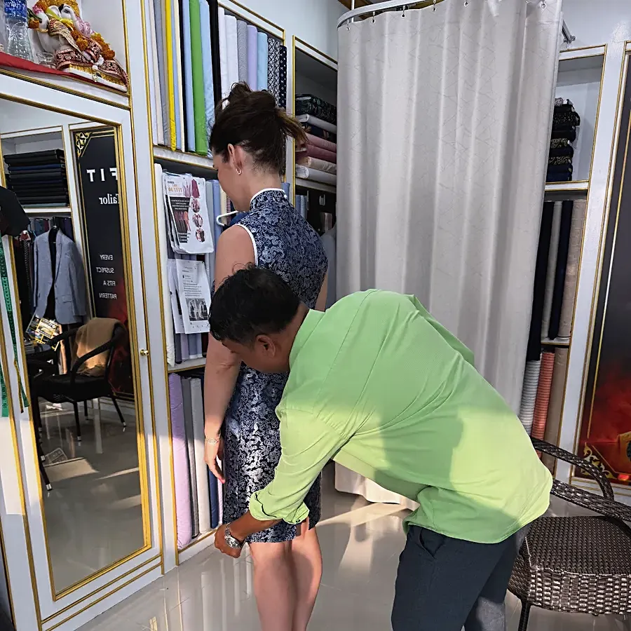 A tailor adjusting the hem of a client's blue patterned dress at a fitting in the shop — from Szabina Zseli's review